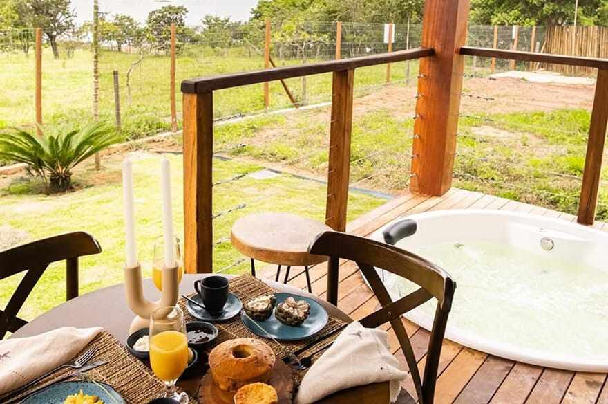 Varanda do bangalô com mesa de café da manhã e jacuzzi privativa.