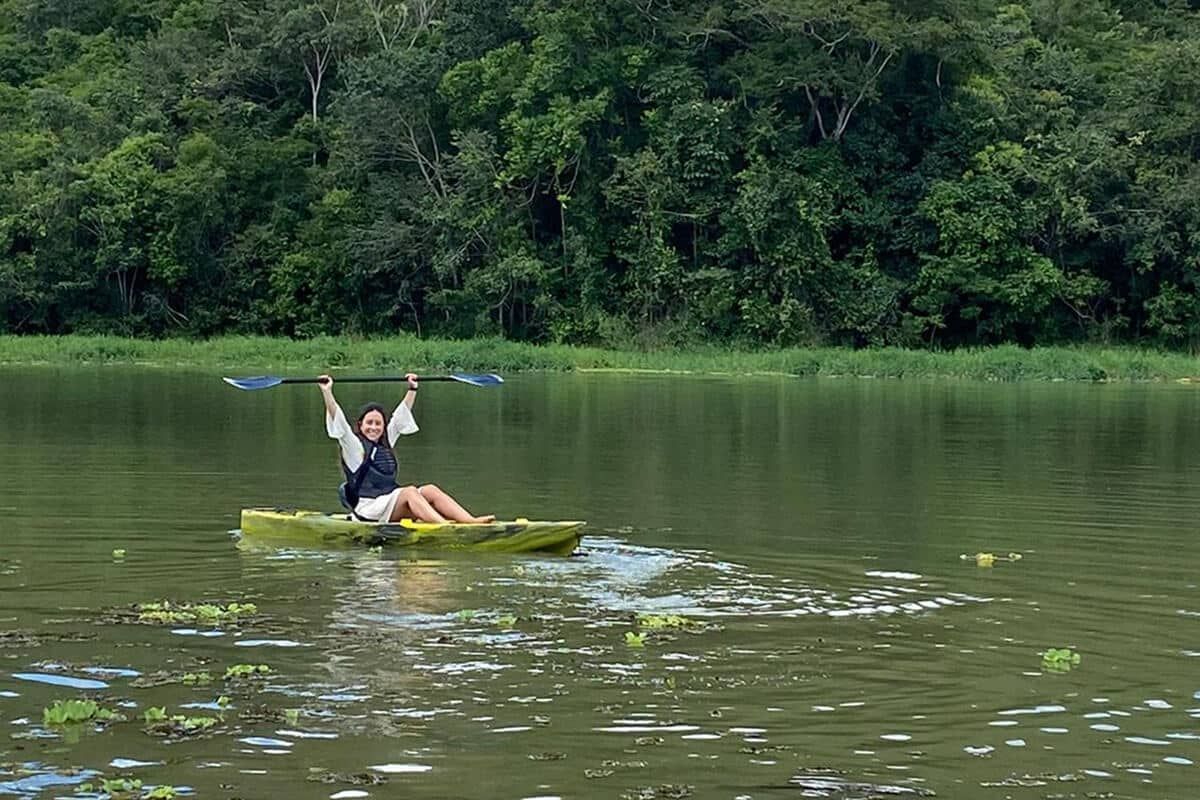 Hóspede em um caiaque amarelo no Lago Corumbá IV, com a mata ciliar densa na margem oposta.
