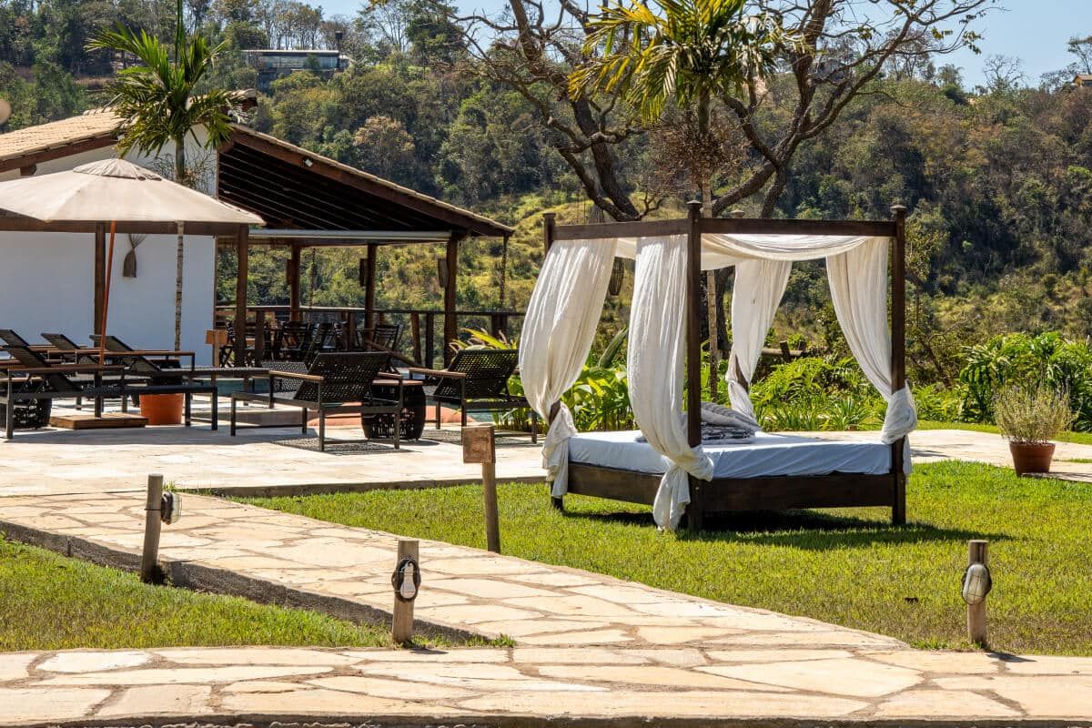 Cama balinesa no gramado ao lado do deck, da piscina e da mata.